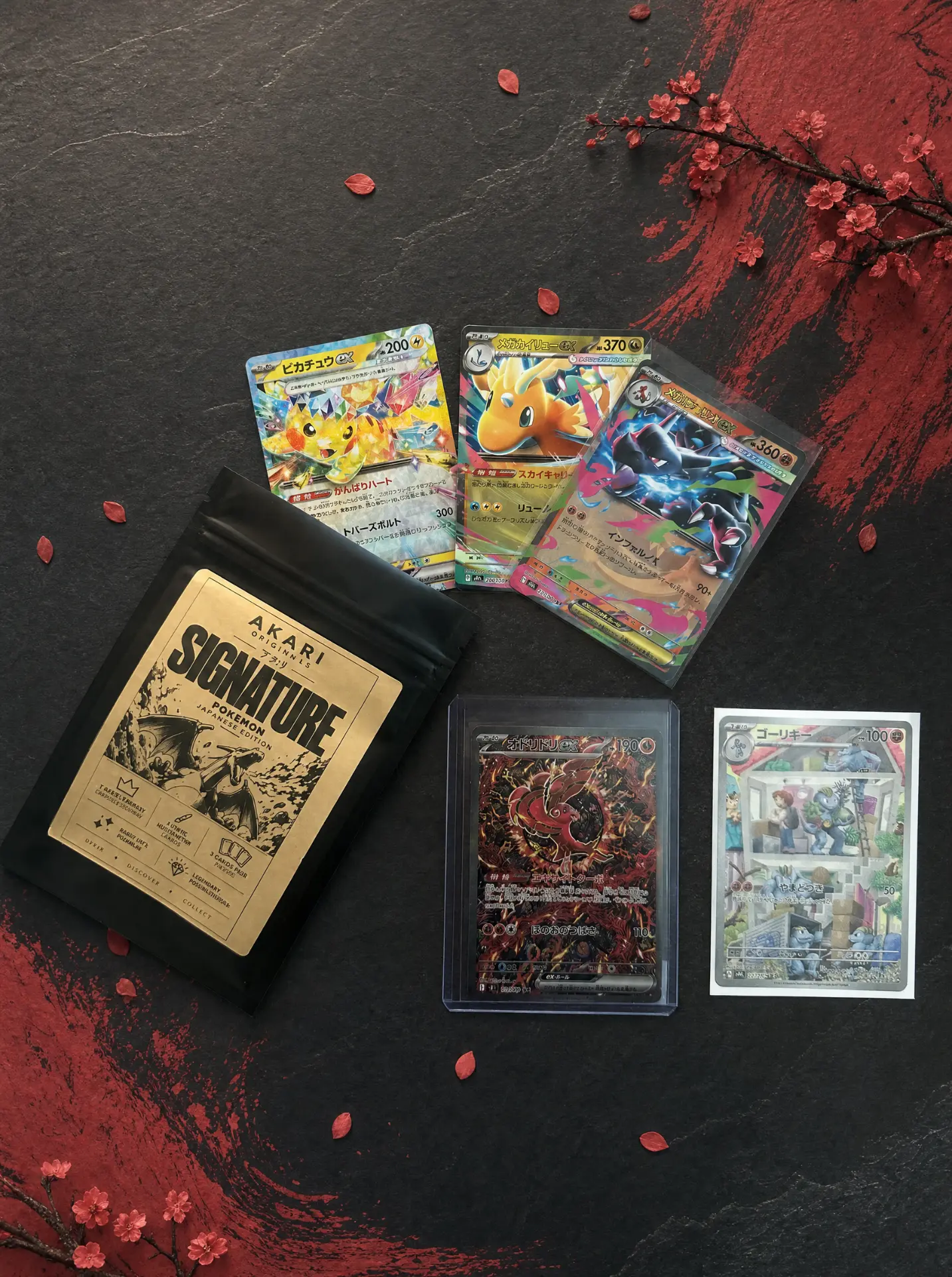 Exemple de contenu Akari Signature Pokémon : cartes japonaises et sachet sur pierre sombre, branchage fleuri